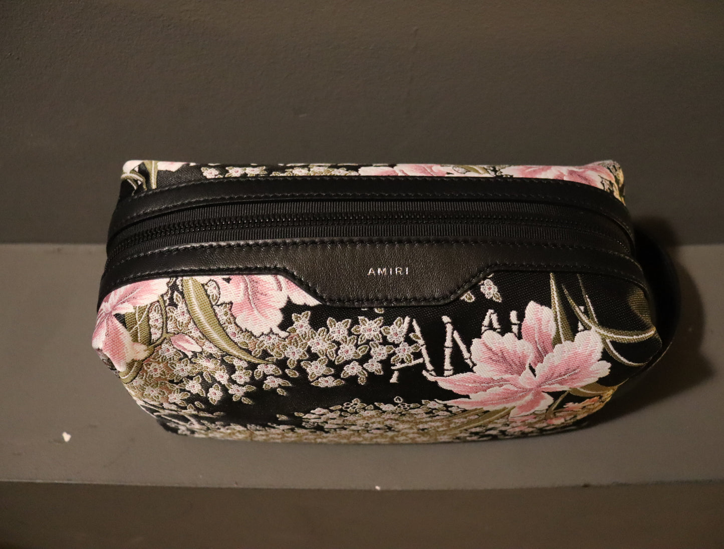 A stylish AMIRI Hibiscus Jacquard Dopp Kit in a multi-colored jacquard fabric, complemented by a twill lining and leather detailing. The AMIRI logo is embroidered on the kit. This kit comes in one size (O/S) and features a vibrant and eye-catching design.