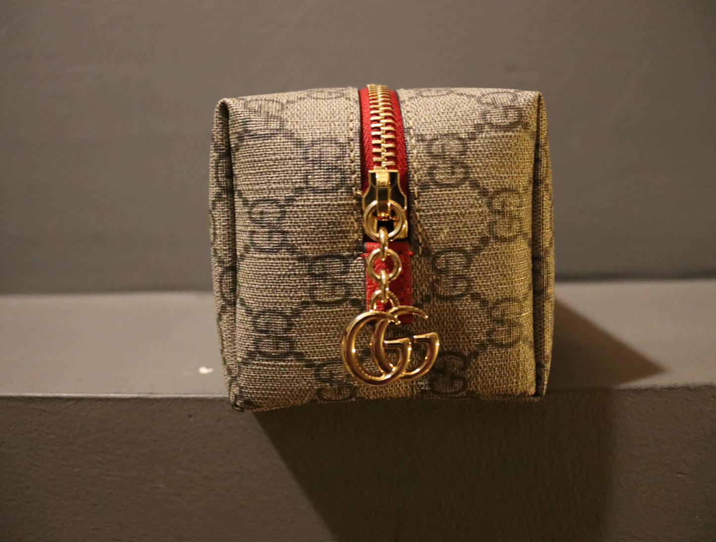 A luxurious Gucci Ophidia GG-Monogram Make-Up Bag crafted from GG-monogram canvas with leather trim and adorned with gold hardware. The bag measures approximately 3.3 inches in length, 7 inches in width, and 3.4 inches in depth. It boasts a striking red exterior and a green interior.