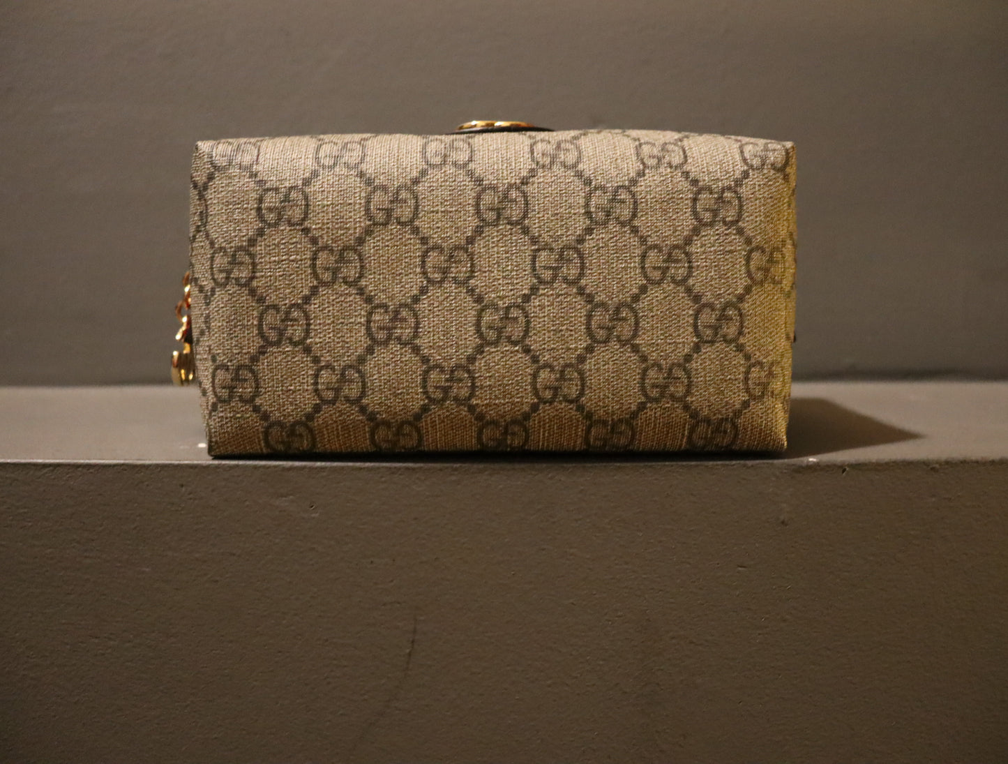 A luxurious Gucci Ophidia GG-Monogram Make-Up Bag crafted from GG-monogram canvas with leather trim and adorned with gold hardware. The bag measures approximately 3.3 inches in length, 7 inches in width, and 3.4 inches in depth. It boasts a striking red exterior and a green interior.