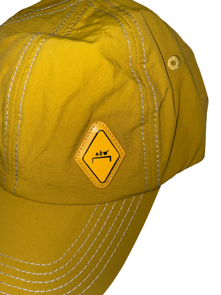 Yellow A-COLD-WALL* Diamond Baseball Cap with a metal A-COLD-WALL* logo on the front, made of durable nylon material, and featuring a bracket closure at the back.